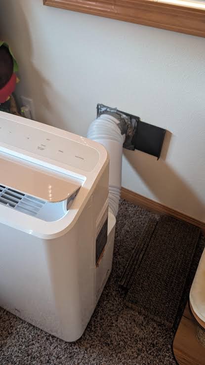 Portable AC exhaust hose fitted with a window kit in an Indian bedroom